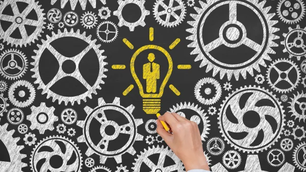 Hand drawing a lightbulb around gears to symbolize an idea